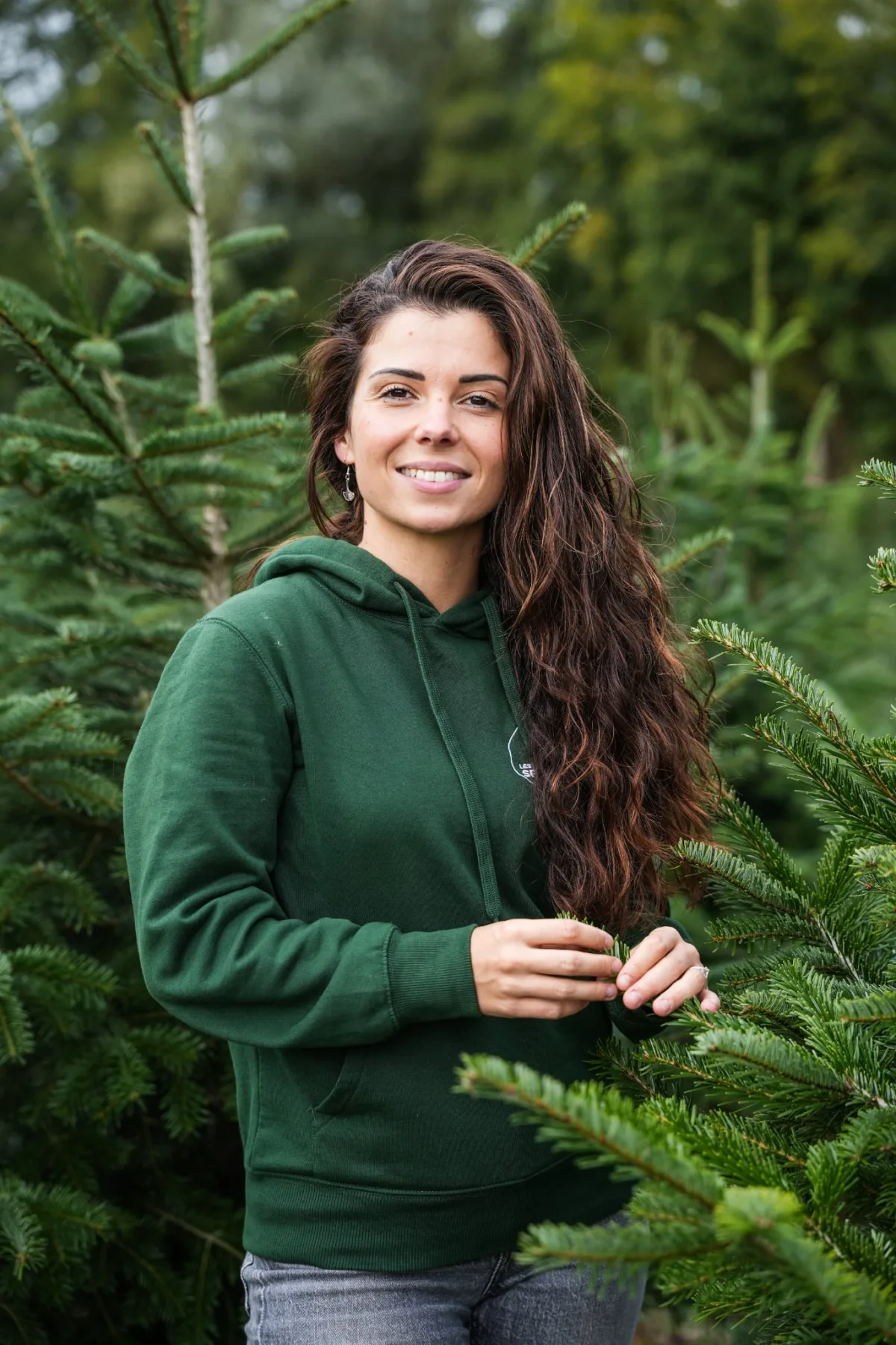 Marine, la communicante de l'équipe, en sweat vert au milieu des sapins